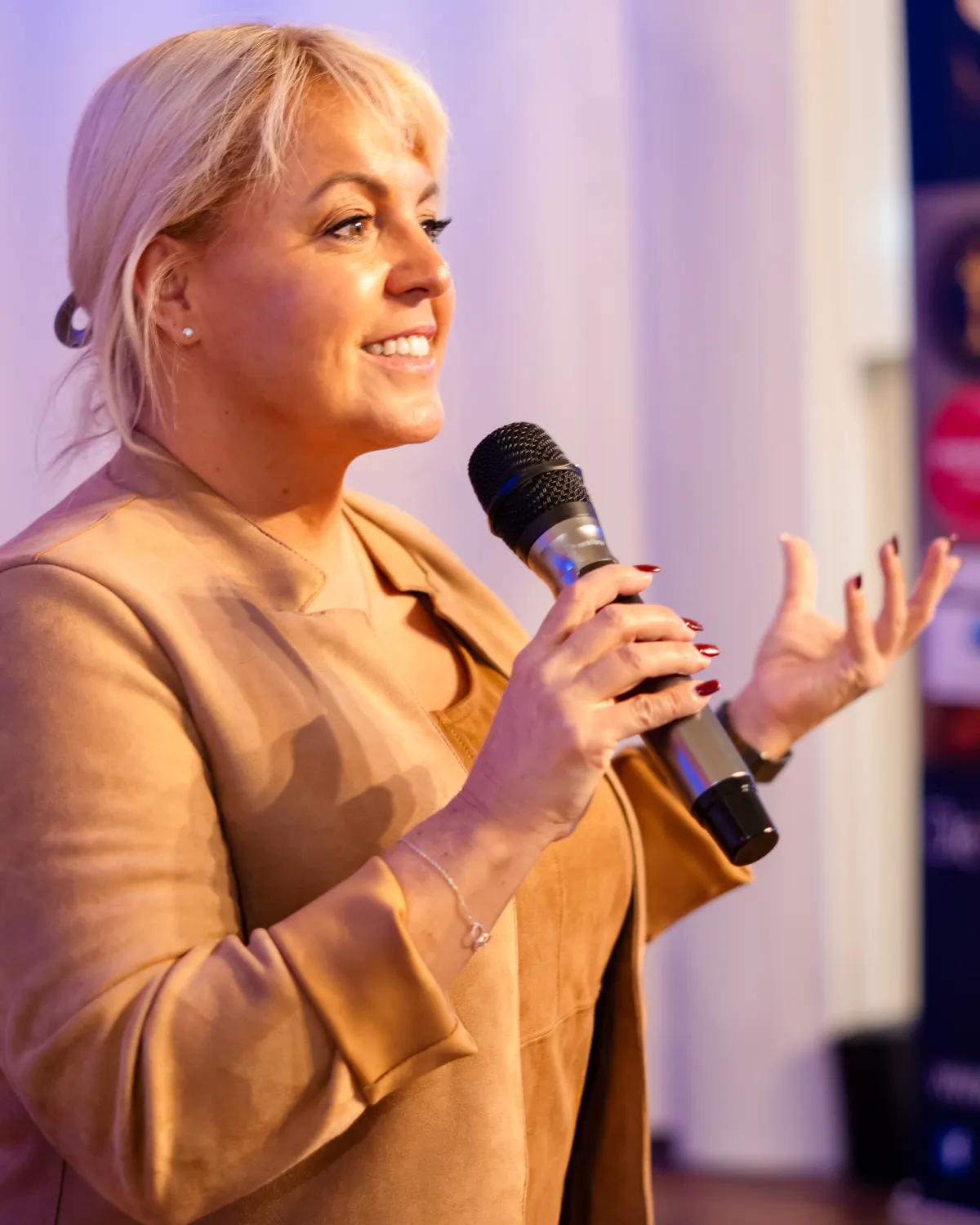 Claudia Conen spricht mit Mikrofon auf einer Veranstaltung
