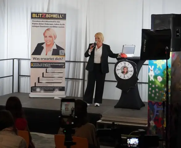 Claudia Conen mit Mikrofon auf einer kleinen Bühne bei einer Benefizveranstaltung